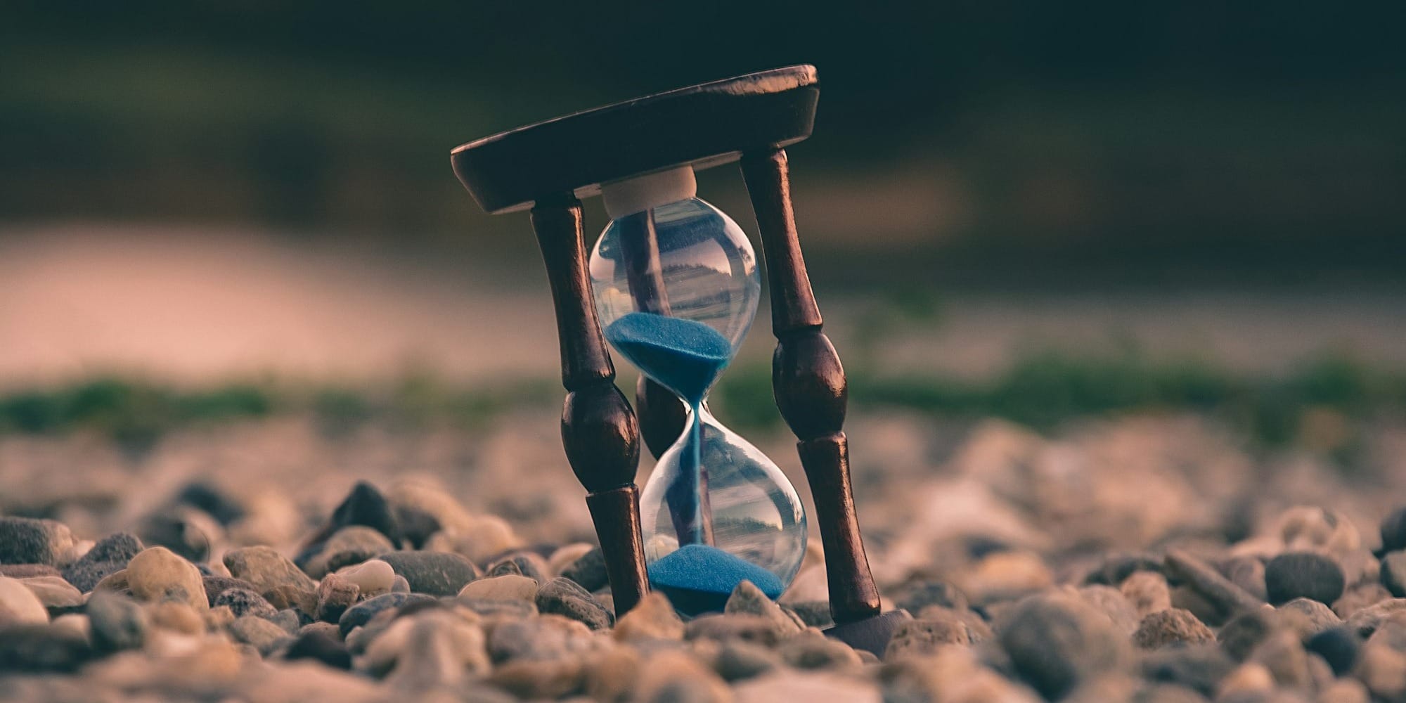 selective focus photo of brown and blue hourglass on stones